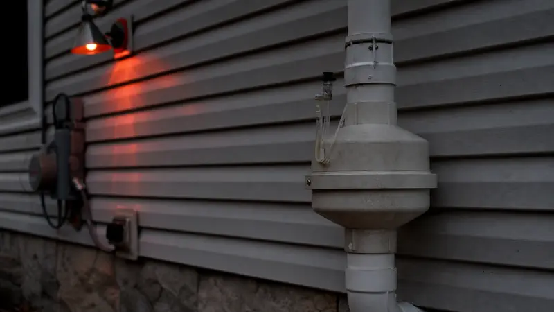 Weathered older radon fan on an exterior wall