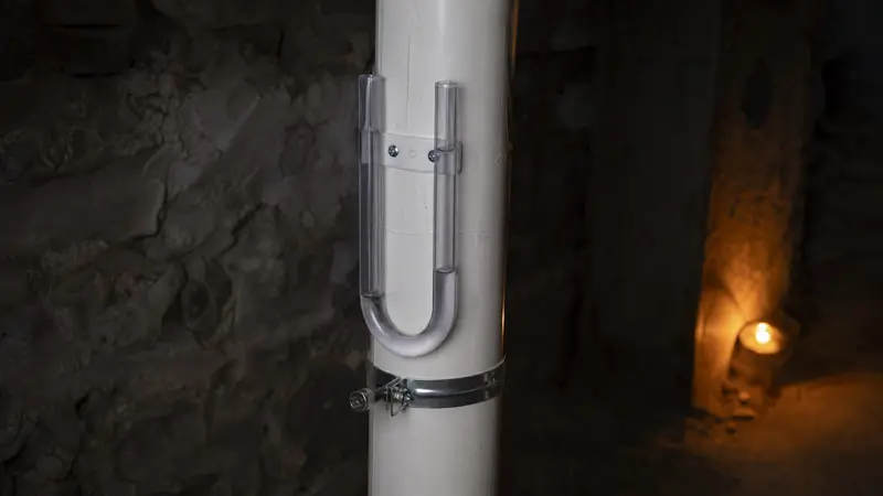 Close view of a U-tube manometer on a white radon pipe